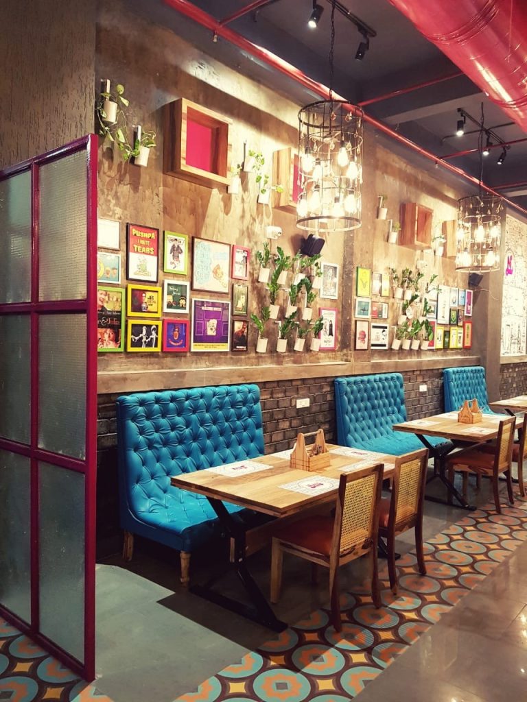 "Rosewood rectangular dining table with sturdy black metal legs at Nini’s Kitchen, Ahmedabad, designed by Kernig Kraft Jodhpur."