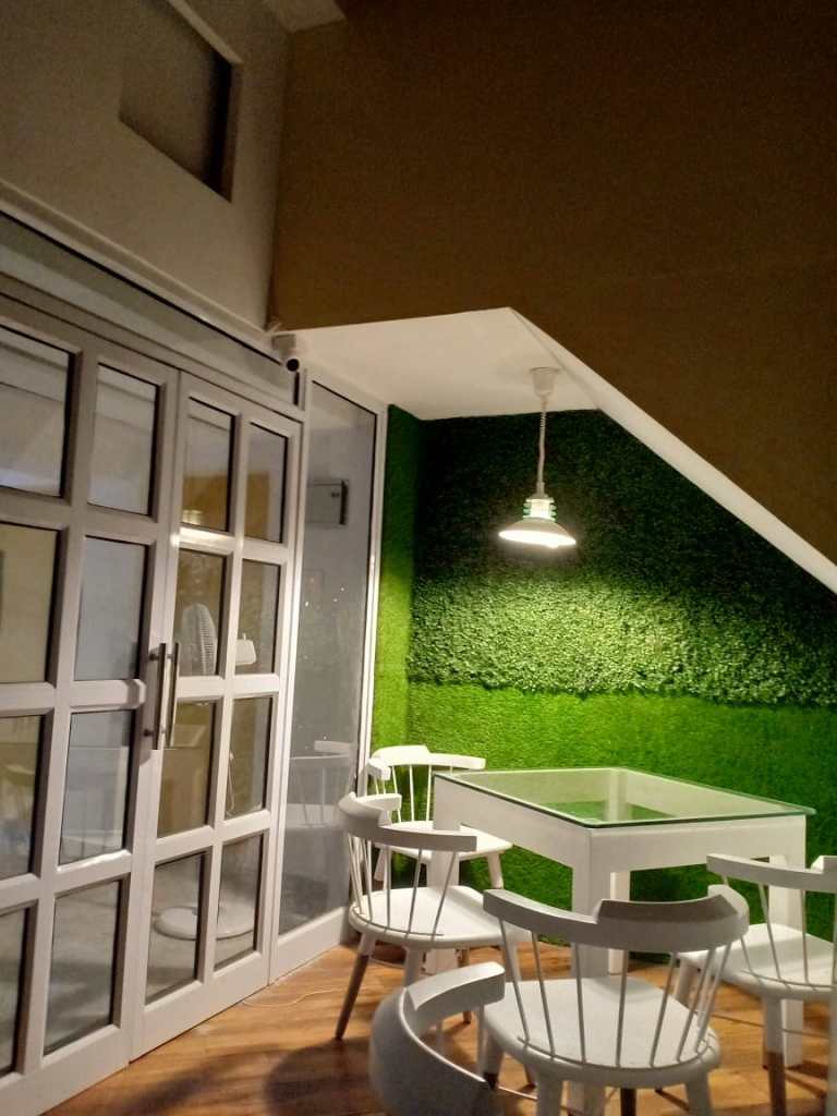 Outdoors, a cafe setup exudes charm. The cafe chairs and glass-topped tables create an inviting atmosphere, where patrons can relish moments of leisure in style by Kernig Krafts.