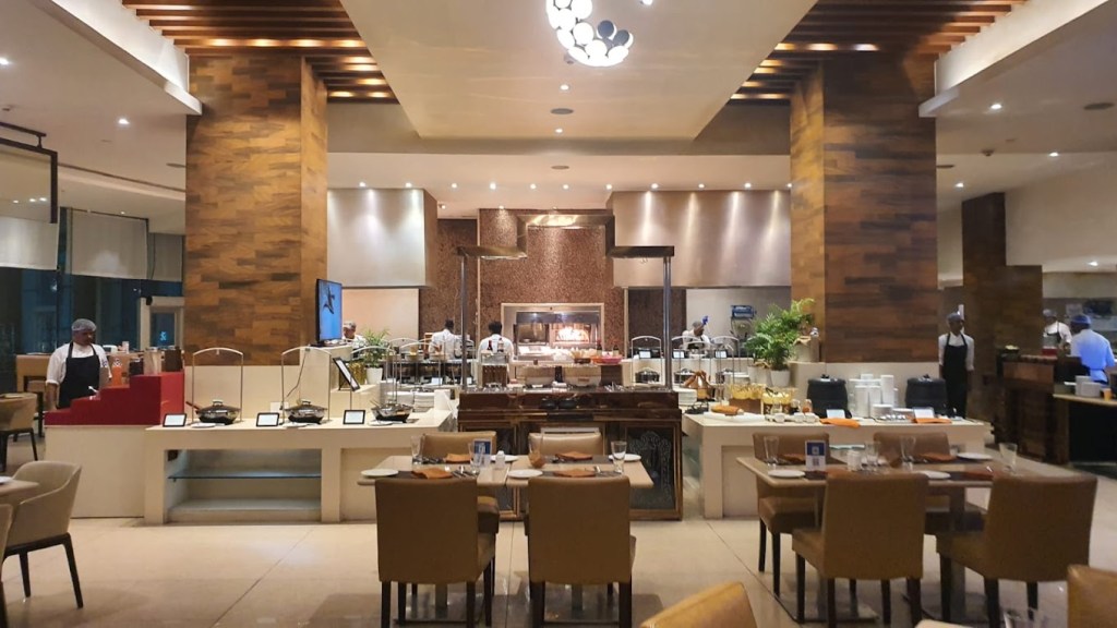 The image showcases a blend of stylish, well-crafted furniture that radiates warmth and charm. With comfortable wooden chairs and tables thoughtfully arranged, it's the perfect setup for a relaxed dining experience. 