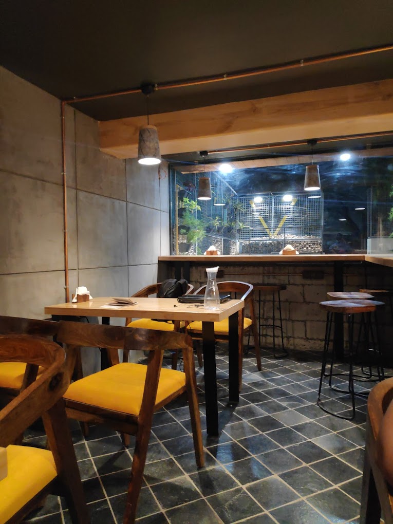 The image showcases a blend of stylish, well-crafted furniture that radiates warmth and charm. With comfortable wooden chairs and tables thoughtfully arranged, it's the perfect setup for a relaxed dining experience. 